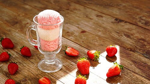 Strawberry and vanilla ice cream in a glass glass. Strawberries on wooden background. Shade from the sun. Summer photo.