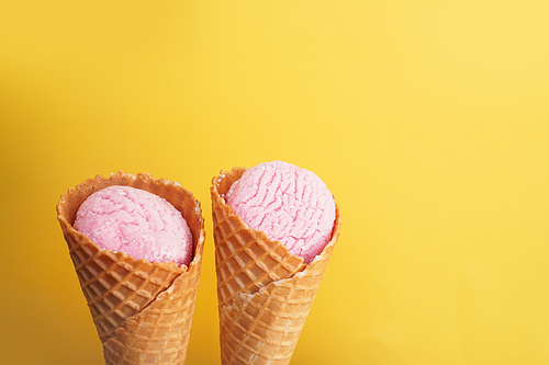 Delicious pink ice cream in a cone on a yellow background. Minimalism Concept.
