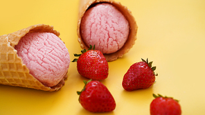 Strawberry ice cream in a waffle cone. Ice cream and berries on a yellow summer background