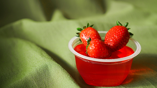 Red strawberry jelly with berries in a plastic container. Sweet dessert for a snack