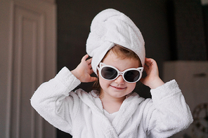 Little girl in a bathrobe and towel, sunglasses. Girl after shower.