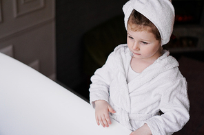 Little girl in a white robe after taking a bath. Hygiene and baby fashion concept