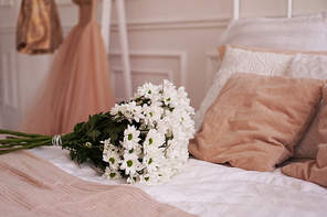 A bouquet of daisies on a bed in a bedroom in a Scandinavian style