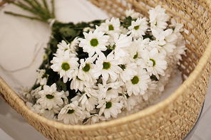 A large bouquet of daisies in a straw basket.