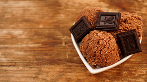 Homemade chocolate ice cream with chocolate pieces in a white bowl. Wooden background
