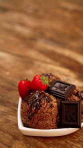Chocolate ice cream in a bowl. Dessert decorated with chocolate and strawberries. Sweets on wooden background