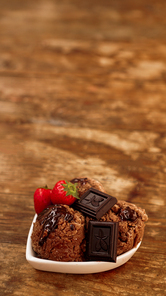 Chocolate ice cream in a bowl. Dessert decorated with chocolate and strawberries. Sweets on wooden background