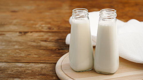 Fresh milk in two glass bottles. Wood rustic background. Healthy eating
