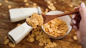 Healthy cornflakes and milk and a wooden spoon on wooden table. Glass bottles with milk for a healthy breakfast