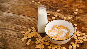 Healthy eating background. Fresh milk in bowl with cornflakes. Wooden background. Milk in a glass bottle
