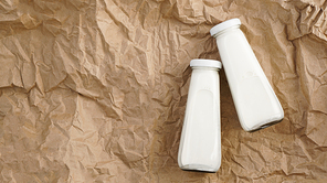 Organic cow milk in glass bottles. Two bottles of milk on crumpled craft paper. Natural milk for health.