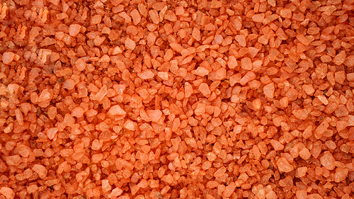 Orange dead sea salt texture background. Solid sea bath salt background. Orange crystals of salt, beauty, health and spa concept