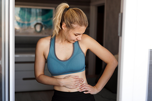 Close up of the woman holding her belly. Pain after home workout. Weight loss, slim body, healthy concept