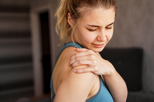 Women wearing athletic suits feeling shoulder pain after exercise at home. The danger of self-training