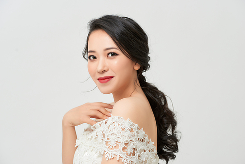 The bride in a magnificent white dress stands back and looks over her shoulder.