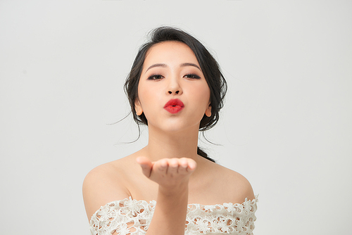 Asian bride with duck face sending air kiss isolated on white