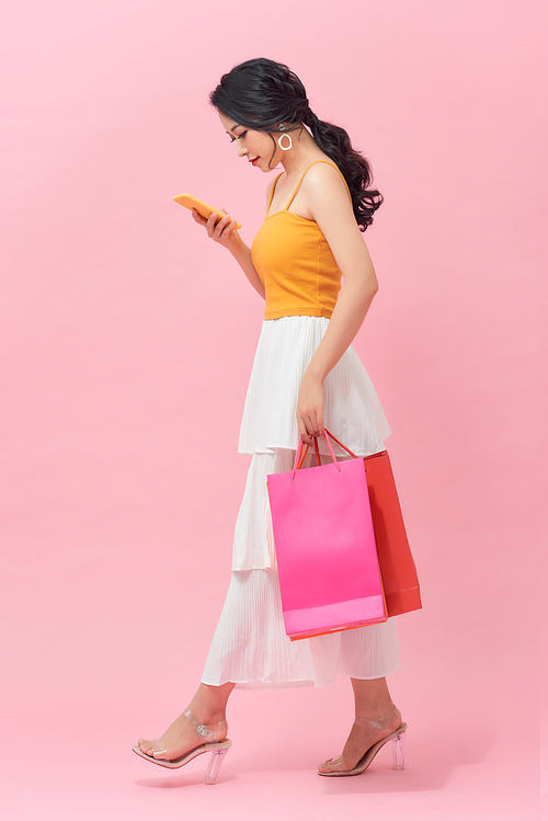 Woman carrying shopping bags and text messaging on the phone