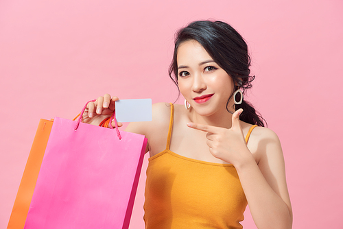 Young beautiful woman holding colorful shopping bags and a credit card