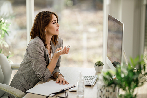 An attractive young woman using a computer to have a web conference at home.