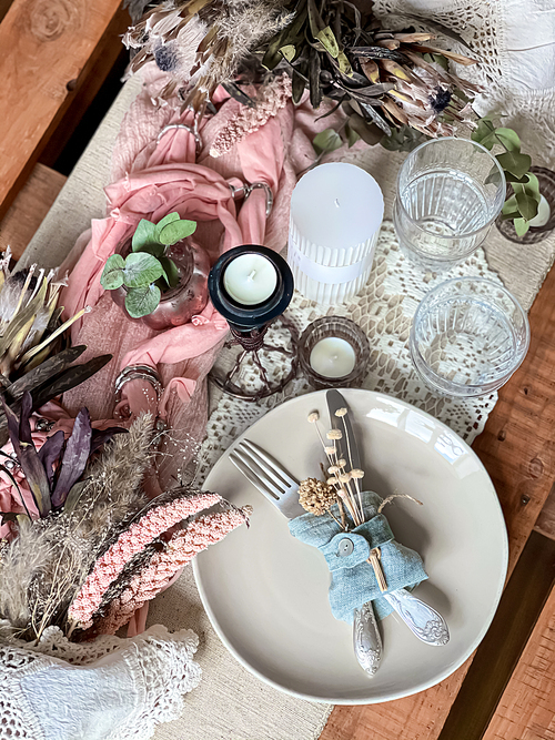 Festive table setting with sprigs of dried flowers and decorative elements.