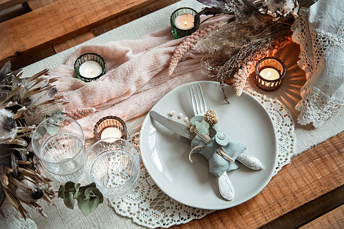 Romantic table setting with burning candles and dried flowers for a wedding or Valentine's Day.