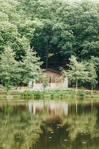 A cabin in front of a lake in the forest during autumn with copy space and colorful leaves and trees