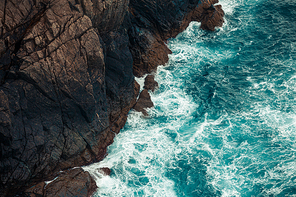 A colorful background of the water breaking against the stones in the coast of spain