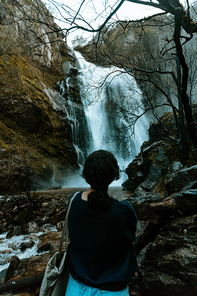 Woman in front of a giant waterfall in the forest during a spring day with copy space