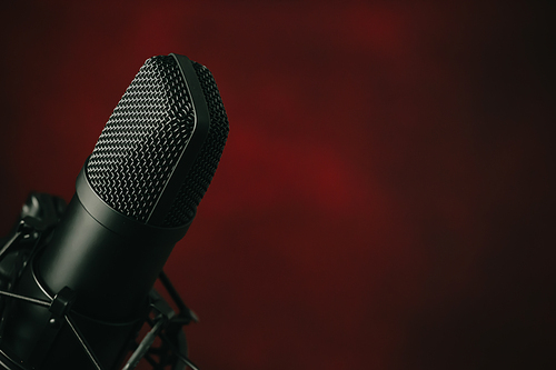 A close up of a streaming microphone over a red background with copy space