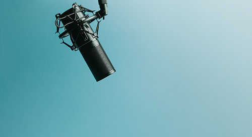 Minimalistic image of a streaming microphone over an pastel blue background with copy space, minimal concept, technology streaming