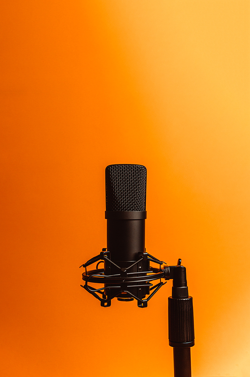 Minimalistic image of a streaming microphone over an orange background with copy space, minimal concept, technology streaming