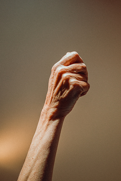 An old woman closed hand rising on pastel tones with lights