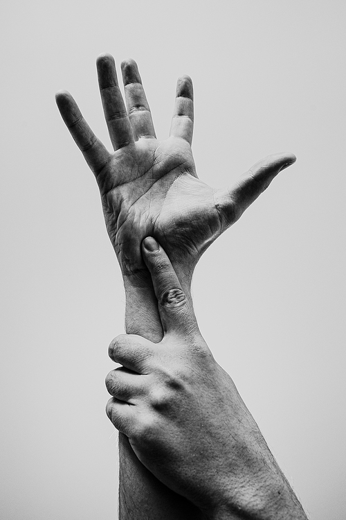 Two young hands, one grabbing the another, in black and white with a lot of texture