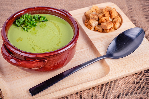 Fresh asparagus creamy soup and ingredients on wooden table on rustic wooden background, selective focus