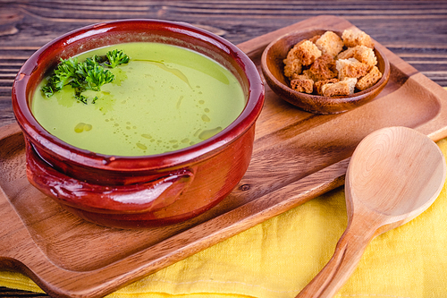 Fresh asparagus creamy soup and ingredients on wooden table on rustic wooden background, selective focus