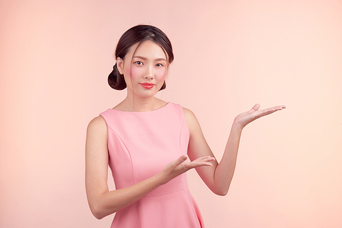 Fashion portrait of a beautiful young woman in a pretty dress over pink background