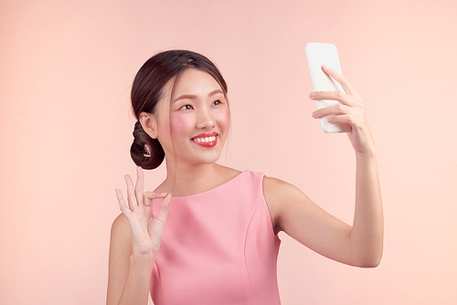 Fashion portrait of a beautiful young woman in a pretty dress over pink background