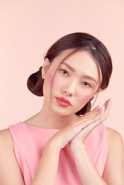 Beautiful asian girl with professional makeup and stylish hairstyle  isolated on pink. Cosmetics and make-up