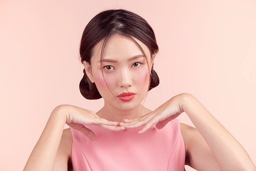 Fashion portrait of a beautiful young woman in a pretty dress over pink background