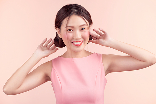 Fashion portrait of a beautiful young woman in a pretty dress over pink background