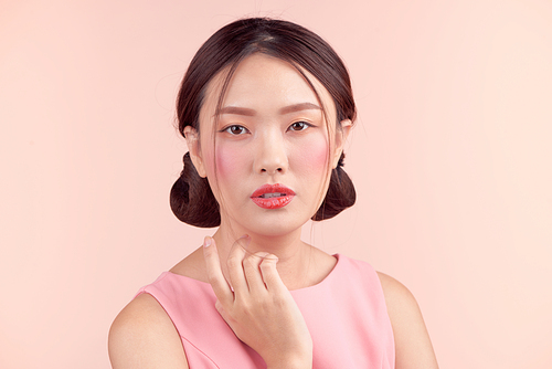 Fashion portrait of a beautiful young woman in a pretty dress over pink background