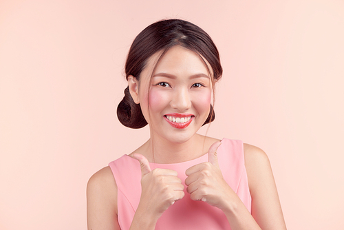 Fashion portrait of a beautiful young woman in a pretty dress over pink background