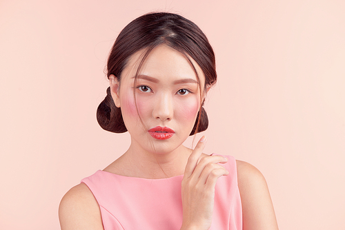 Fashion portrait of a beautiful young woman in a pretty dress over pink background