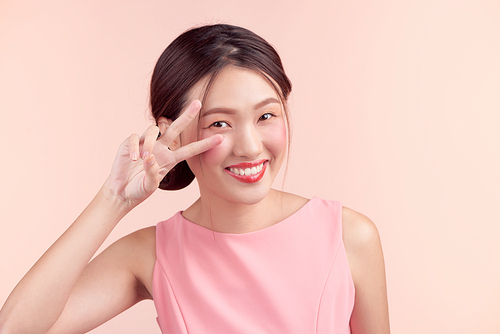 Beautiful asian girl with professional makeup and stylish hairstyle  isolated on pink. Cosmetics and make-up