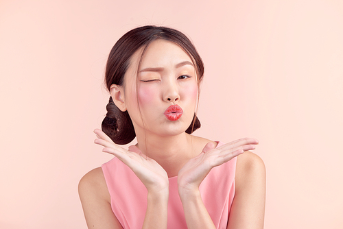 Fashion portrait of a beautiful young woman in a pretty dress over pink background