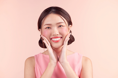 Fashion portrait of a beautiful young woman in a pretty dress over pink background