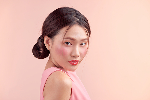 Fashion portrait of a beautiful young woman in a pretty dress over pink background