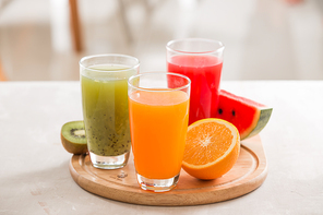 Fresh juices smoothie three glass red green orange tropical fruits water melon, kiwi, orange. Selective focus