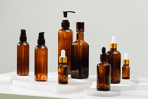 Spa cosmetics in brown glass bottles on gray concrete table. Copy space for text. Beauty blogger, salon therapy, branding mockup, minimalism concept