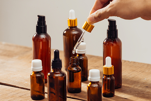 Essential oils bottles on wooden desk with candlelight beside. Spa wellness set.